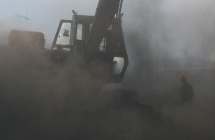 A man is shrouded in coal dust as a bulldozer loads coal onto a truck  at a railway yard in Chandigarh, India.(Reuters/Ajay Verma)