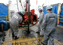 Workers change drilling pipes on the rotary table of a drilling rig. (REUTERS/Tim Shaffer)