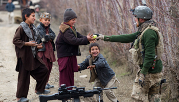 A German soldier of the International Security Assistance Force gives a tennis ball to Afghan children. (REUTERS/Thomas Peter)