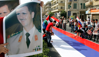 Supporters of Syrian President Bashar al-Assad sign a Russian flag during a rally. (REUTERS/Khaled Al Hariri)