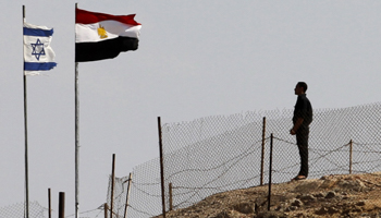 An Egyptian soldier stands near the Egyptian national flag and Israeli flag at the Taba crossing between Egypt and Israel. (REUTERS/Mohamed Abd El Ghany)