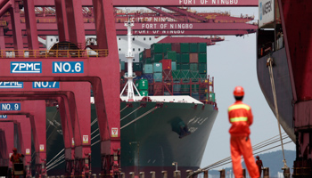 An employee stands next to a container ship at Ningbo port. (REUTERS/Carlos Barria)