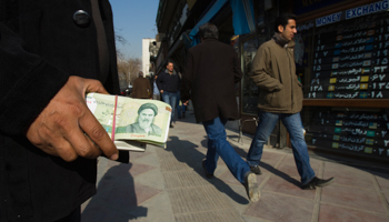 A money changer holds Iranian currency in Tehran's business district (REUTERS/Raheb Homavandi)