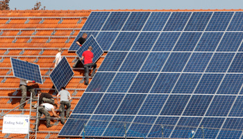 Workers install solar panels on a roof in Germany (REUTERS/Michaela Rehle)