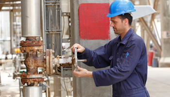 A worker adjusts the valve of an oil pipe at the al-Doura refinery in Baghdad (REUTERS/Mohammed Ameen)