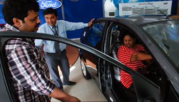 An employee speaks to potential customers at a car showroom in Mumbai (REUTERS/Danish Siddiqui)