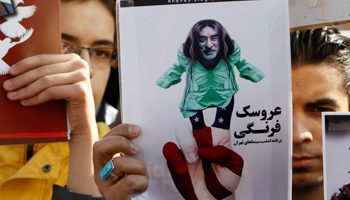 A man holds a caricature of reformist opposition leader Mir Hossein Moussavi during a pro-government rally (REUTERS/Raheb Homavandi)