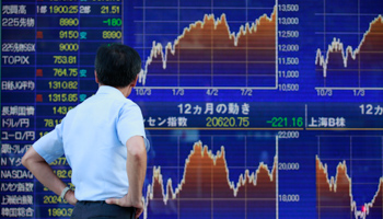 A man looks at a board displaying market indices in Tokyo (REUTERS/Yuriko Nakao)