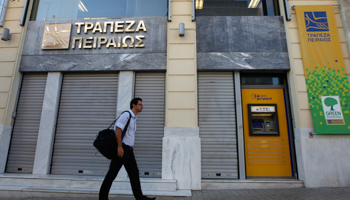 A man walks in front of a Piraeus bank branch in central Athens (REUTERS/John Kolesidis)