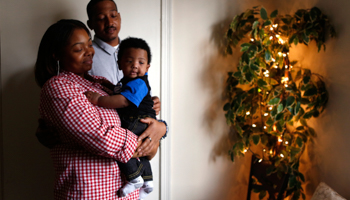 A couple stand with their baby in their apartment in Washington (REUTERS/Kevin Lamarque)