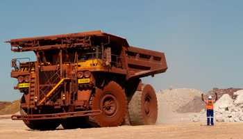 A worker signals to a Haul truck driver at Kumba Iron Ore (REUTERS/Siphiwe Sibeko)