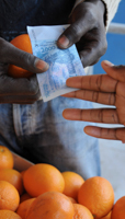 A vendor receives a euro-pegged CFA banknote at a street market in Dakar (REUTERS/Stringer)
