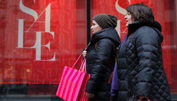 Shoppers walk past a shop while carrying shopping bags in New York (REUTERS/Eduardo Munoz)