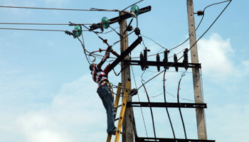 A power official works on an electric pole in Lagos (REUTERS/Akintunde Akinleye)