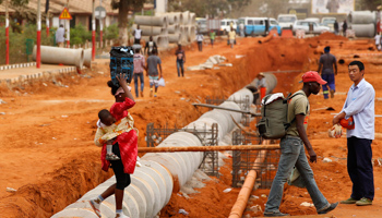 A Chinese worker looks on as locals cross a construction site in Viana, Angola (REUTERS/Siphiwe Sibeko)