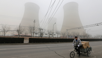 A man cycles past a coal-fired power plant in Beijing (REUTERS/Jason Lee)