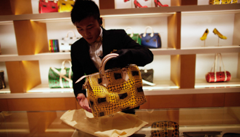 A vendor shows a bag to a customer in Shanghai (REUTERS/Carlos Barria)