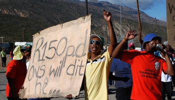 Striking farm workers carry a placard demanding a minimum wage of 150 Rand (REUTERS/Mike Hutchings)