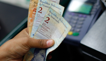 A cashier counts notes at a supermarket in Caracas (REUTERS/Fabian Bimmer)