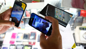 A person holds fake iPhones being sold at a mobile phone stall in Shanghai  (REUTERS/Aly Song)