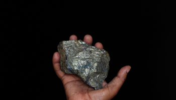 A mine employee shows a piece of copper ore (REUTERS/James Akena)