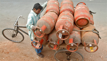 A worker loads gas cylinders onto his cycle-rickshaw (REUTERS/Rupak De Chowdhuri)