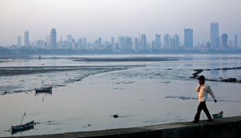 A man walks along a wall overlooking Mumbai's financial district (REUTERS/Vivek Prakash)