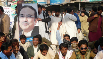 PPP supporters display a poster of President Asif Ali Zardari (REUTERS/Stringer)