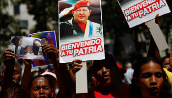 Supporters of President Hugo Chavez hold pictures of him as they gather at Plaza Bolivar in Caracas (REUTERS/Carlos Garcia Rawlins)