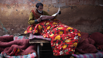 A homeless man reads newspapers in the old quarters of Delhi (REUTERS/Ahmad Masood)