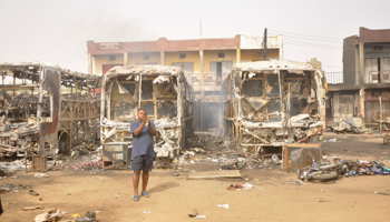 A man stands in front of some burnt buses after explosions in Kano (REUTERS/Stringer)