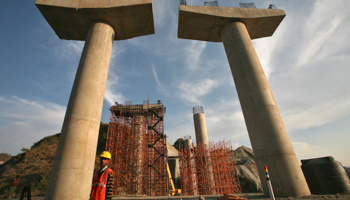 Workers stand at a construction site of a bridge (REUTERS/Mukesh Gupta)