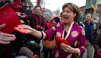 British Columbia Premier Christy Clark hands out red packets during the Chinese New Year parade in Vancouver (Reuters/Ben Nelms)