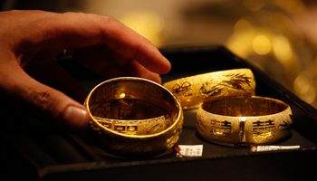 A shop attendant shows gold bracelets to a customer inside a jewellery store in Hong Kong (Reuters/Bobby Yip)