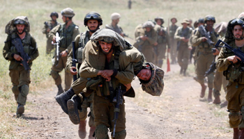 An Israeli soldier carries another soldier as they walk with their comrades during training close to the ceasefire line between Israel and Syria (Reuters/Baz Ratner)