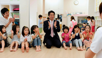 Shinzo Abe plays with children as he inspects a daycare centre in Yokohama (Reuters/Kyodo)