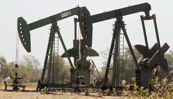 A worker examines a pump on an ONGC well (Reuters/Amit Dave)