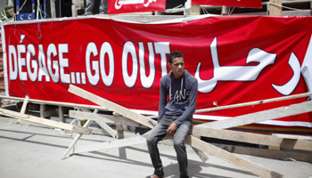 An anti-Morsi protester sits in front of a banner (Reuters/Asmaa Waguih)