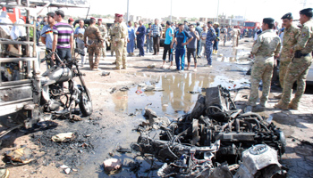 Iraqi army personnel and people gather at the site of a car bomb attack in the city of Kut (Reuters/Jaafer Abed)