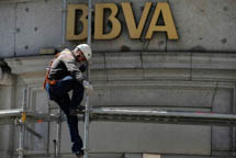 An operator places a piece of scaffolding on the wall of a BBVA bank branch (Reuters/Eloy Alonso)