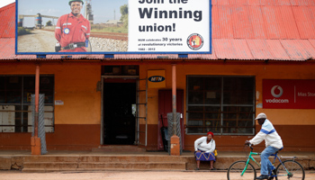 A woman sits beneath a recruitment poster for the National Union of Mineworkers (Reuters/Mike Hutchings)