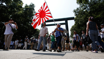 A family holds Japan's rising sun flag as they visit Yasukuni Shrine in Tokyo (Reuters/Issei Kato)