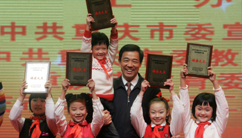 China's former Chongqing Municipality Secretary Bo Xilai holds up a student as he poses for group photographs (Reuters/Stringer)