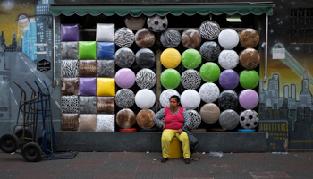 A woman sits in front of a shop selling stools in Sao Paulo (Reuters/Nacho Doce)