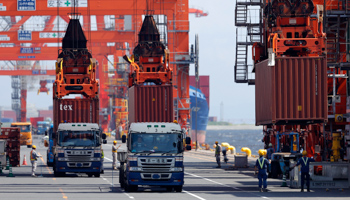 Workers load containers from trucks onto a cargo ship at a port in Tokyo (Reuters/Toru Hanai)