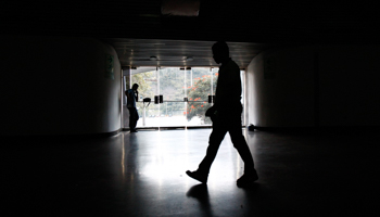 A security guard walks past an exit door as he waits for the power to return after a blackout (Reuters/Carlos Garcia Rawlins)