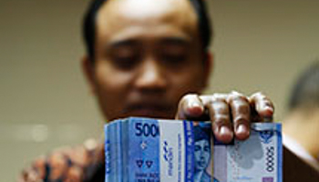 A money changer stacks Indonesian rupiah notes (Reuters/Beawiharta)