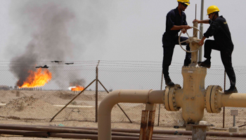 Workers adjust a valve of an oil pipe southeast of Baghdad (Reuters/Atef Hassan)