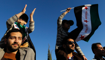 Syrian refugees wave a flag during a protest against Syria's President Bashar al-Assad in Amman (Reuters/Muhammad Hamed)