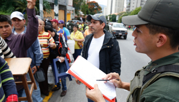 A Venezuelan soldier controls the crowd as people wait to shop for electronic goods outside an appliance store in Caracas (Reuters/Carlos Garcia Rawlins)